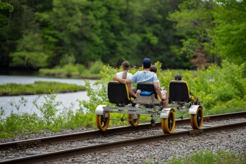 a person riding on the back of a train going down the river